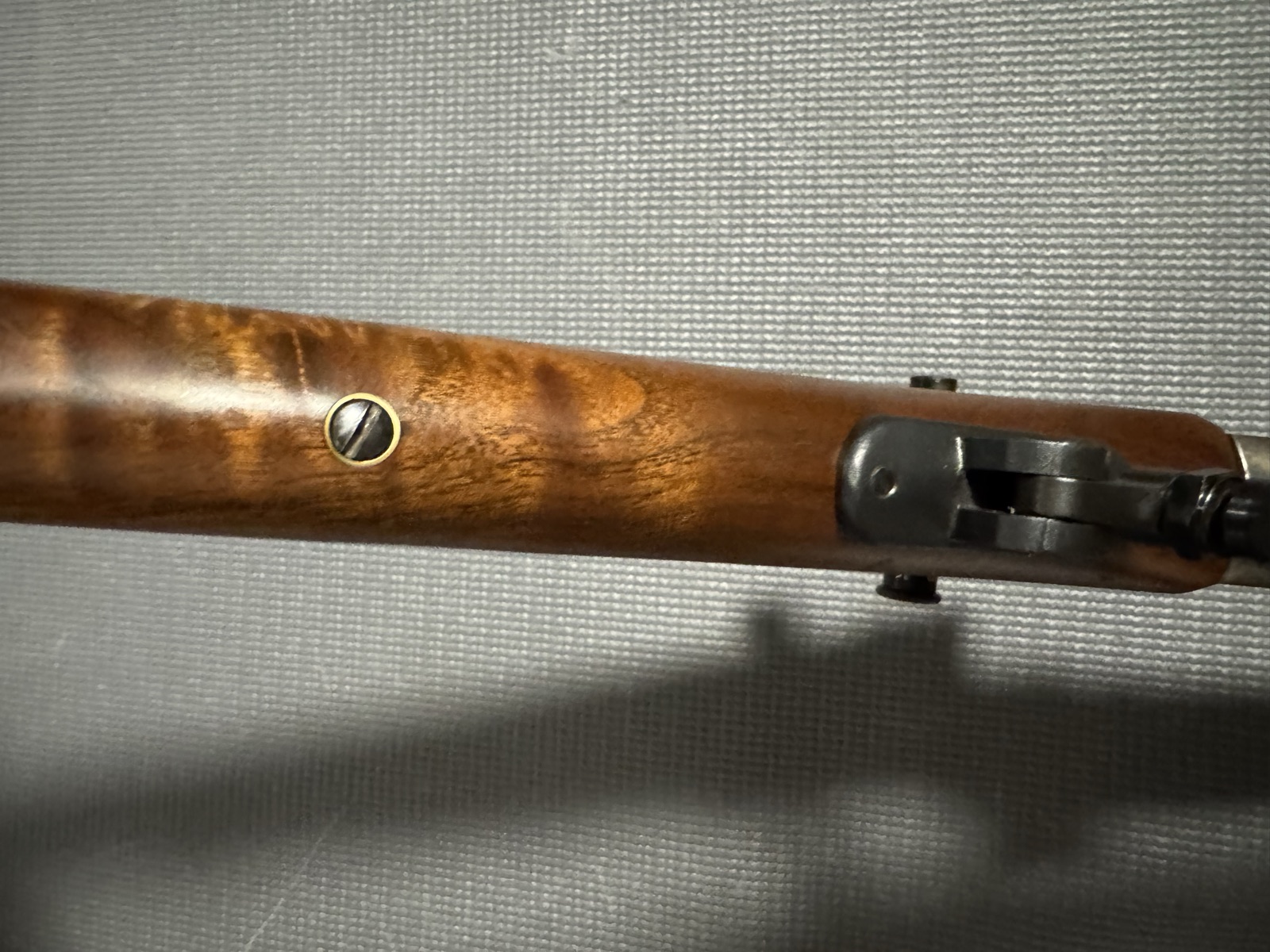 Underside of the forend showing the palm-rest mounting hardware and escutcheoned screw